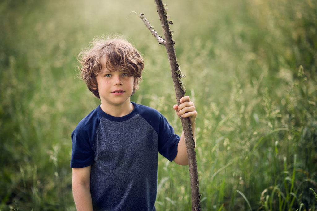 choosing a family photographer for beautiful portrait of child holding stick outdoors